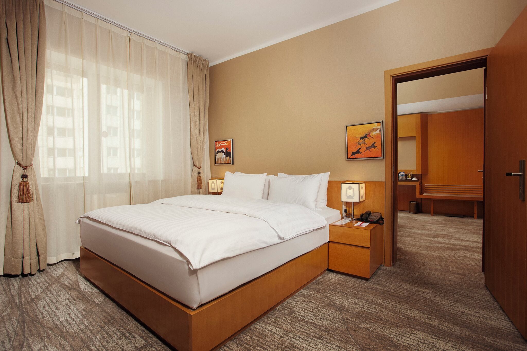 Una habitación de hotel con una cama grande, mesitas de noche, un escritorio y un armario.
