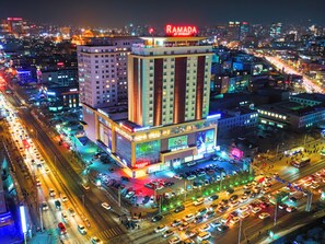 A multi-story hotel with a prominent sign, multiple floors, and a busy street in the foreground. - Ramada by Wyndham Ulaanbaatar Citycenter (Ulaanbaatar)