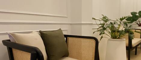 A modern living room with a sofa, a glass coffee table, and a potted plant.