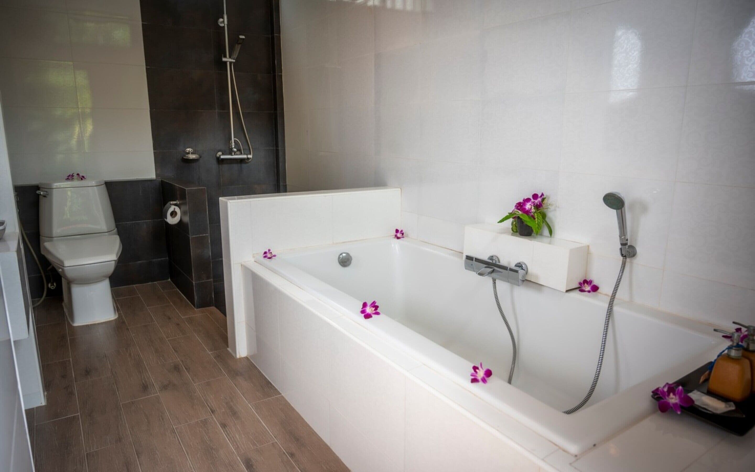 Un baño moderno con una bañera blanca, un inodoro y una zona de ducha.