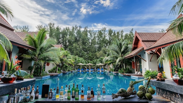A poolside bar with various bottles and tropical decorations. - L'esprit de Naiyang Beach Resort (Sa Khu)