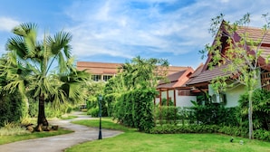 A pathway leading to a building with a red roof, surrounded by lush greenery and palm trees. - L'esprit de Naiyang Beach Resort (Sa Khu)