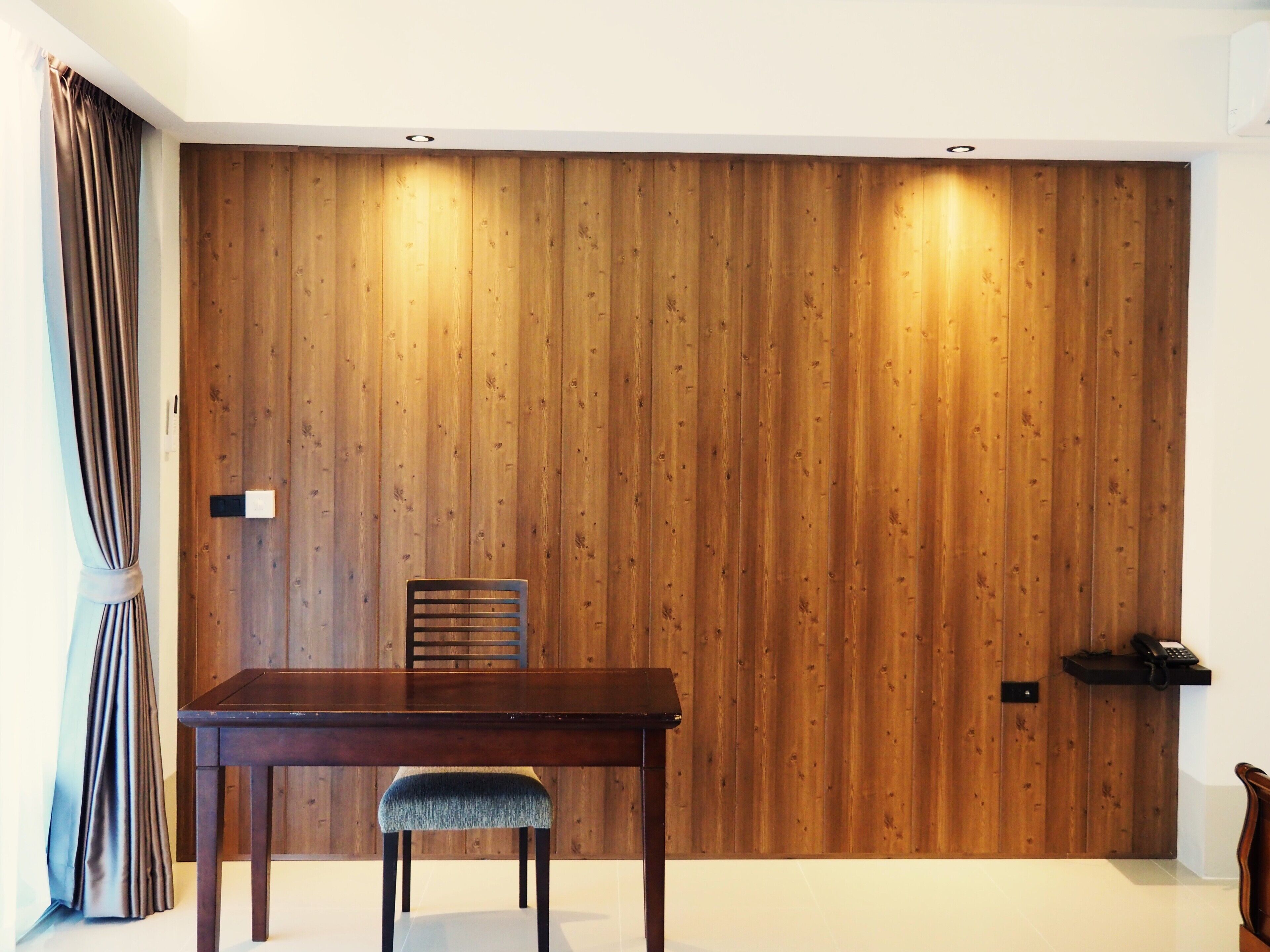 Un comedor con pared de paneles de madera, una mesa y una silla.
