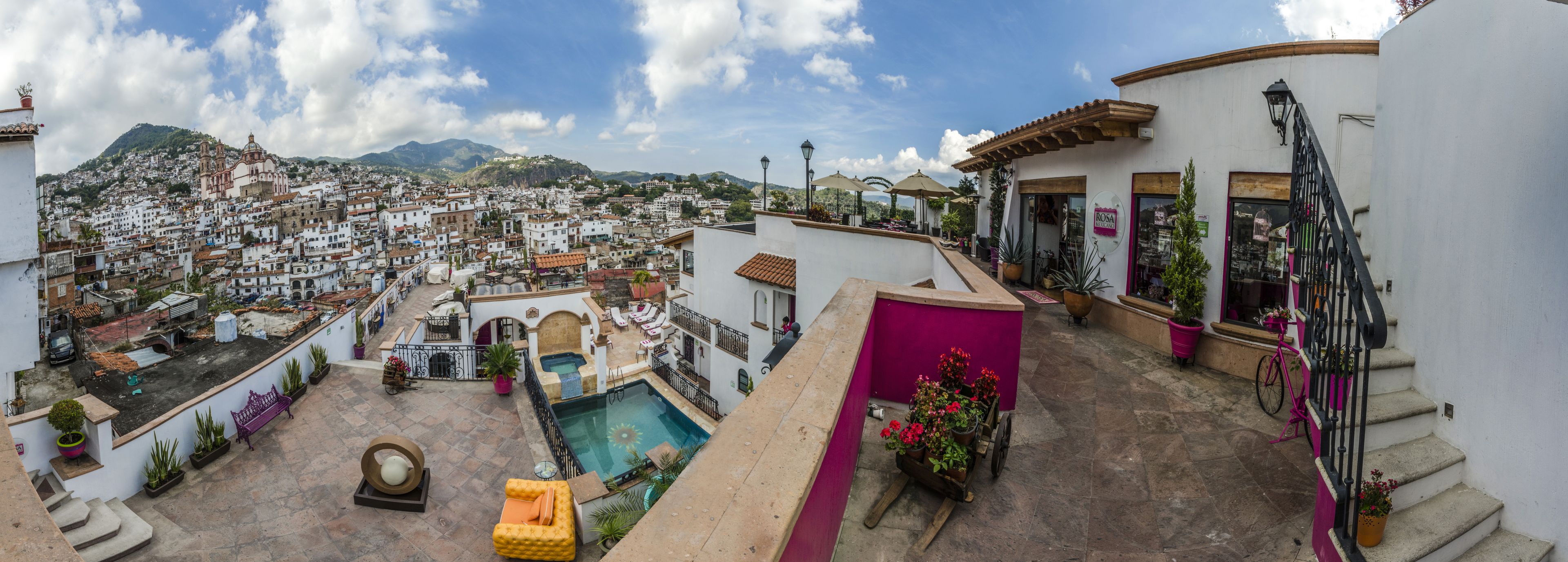 A rooftop pool area with a view of a densely packed town and mountains in the background.