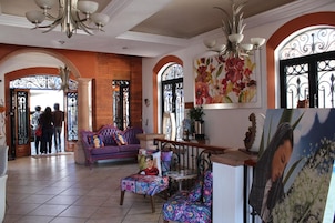 Un vestíbulo amplio con un sofá púrpura, una mesa de centro y un espejo decorativo.