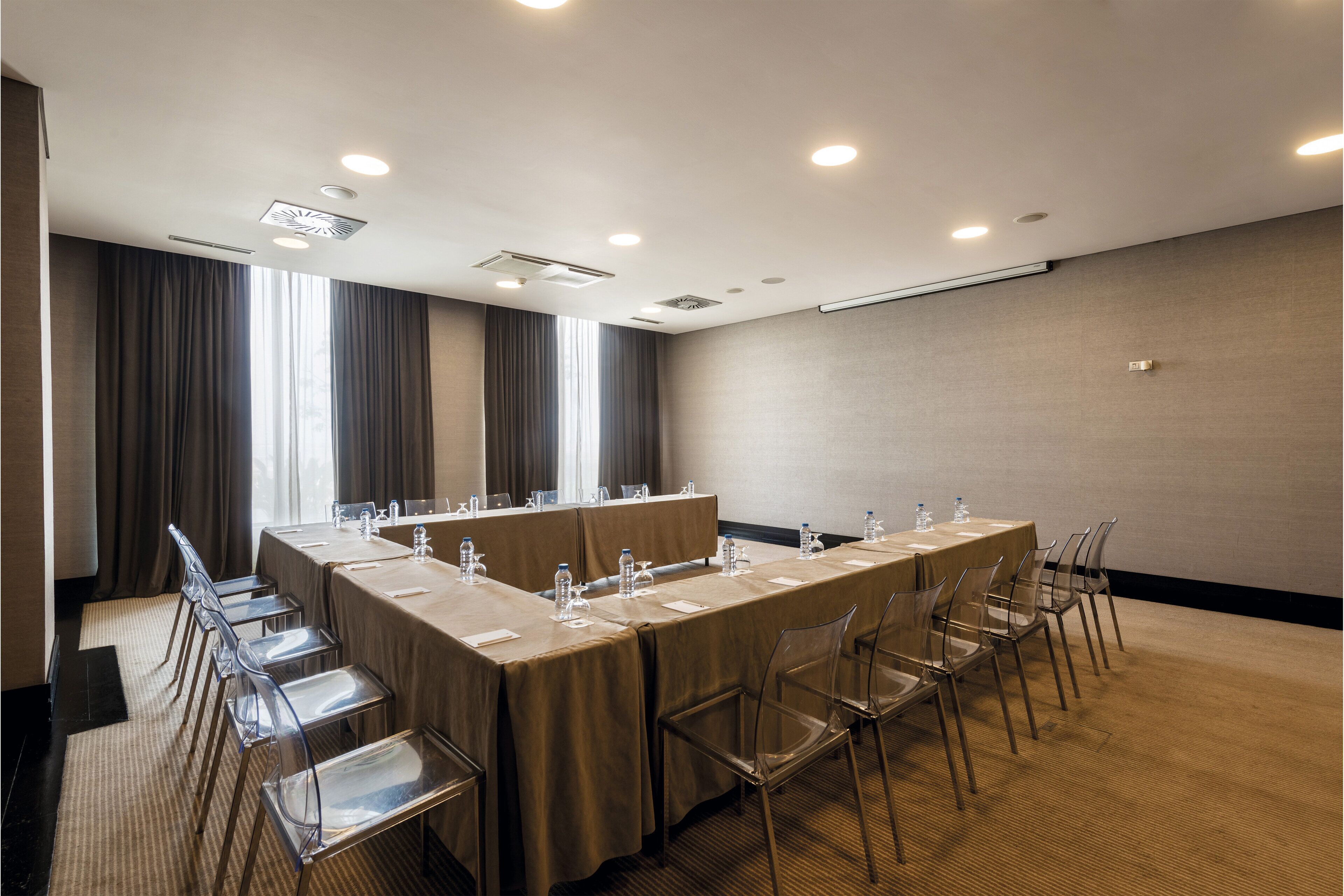 A conference room with a long table, clear chairs, and water bottles.
