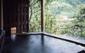 A hot spring area with a wooden bench and a view of lush greenery and a traditional structure in the background. - Seoto Yuoto no Yado UKIHA (Hita)