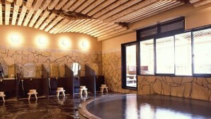 A spa area with a stone wall, wooden ceiling, and a hot tub.