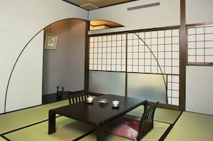 Una habitación tradicional japonesa con suelo de tatami, una mesa baja y paneles shoji.