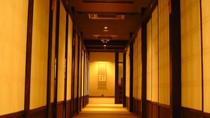 A corridor with wooden paneling and a carpeted floor, leading to a room with a framed picture on the wall.
