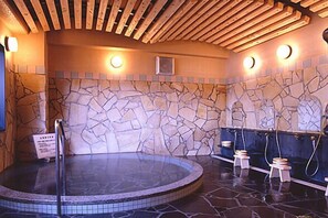 Un espace de bien-être doté d’un mur en pierre, d’un jacuzzi et de bancs en bois.