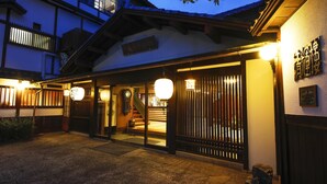 Un edificio japonés tradicional con fachada de madera, una escalera visible y un letrero con caracteres japoneses.