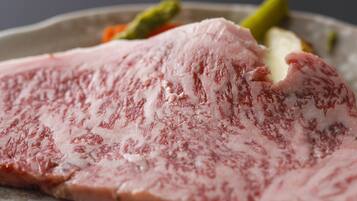 A close-up of a raw pork chop with visible marbling, served on a plate with vegetables.