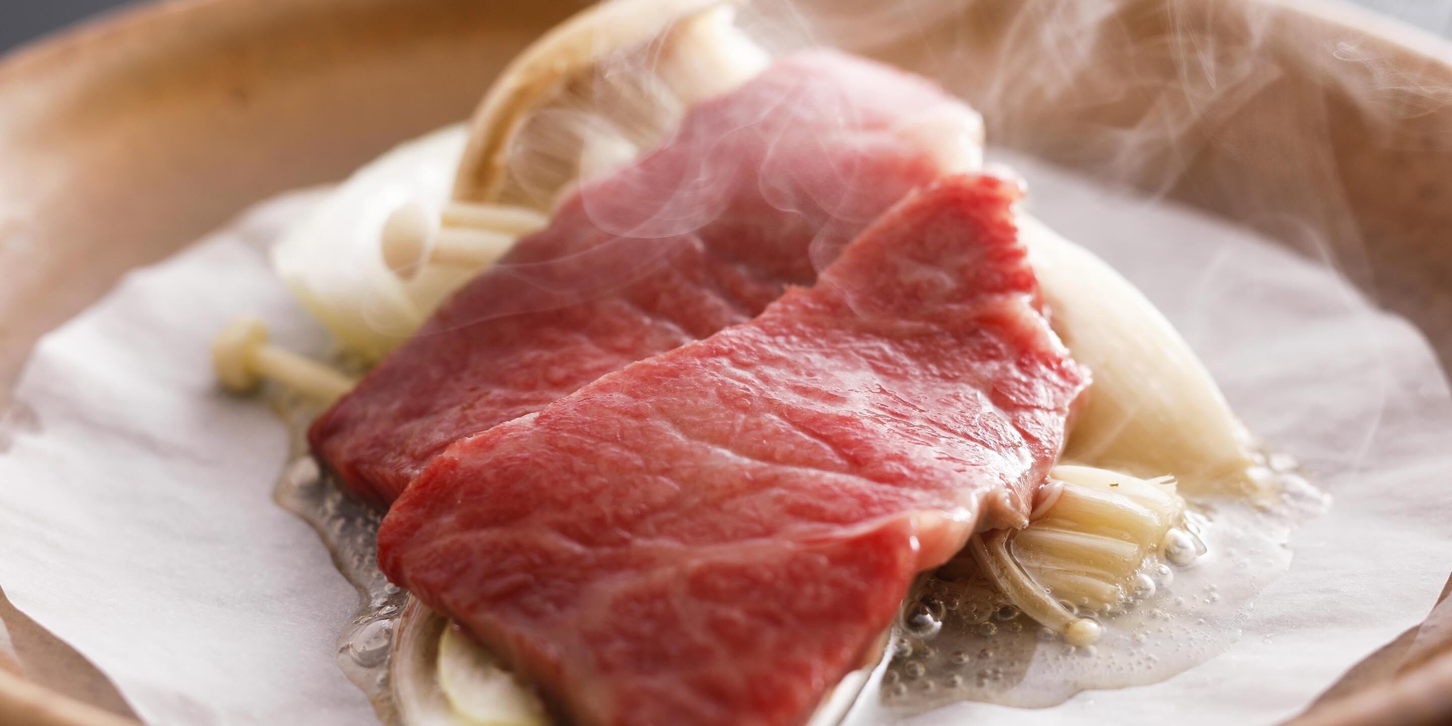 A close-up of raw meat and onions on a white surface.