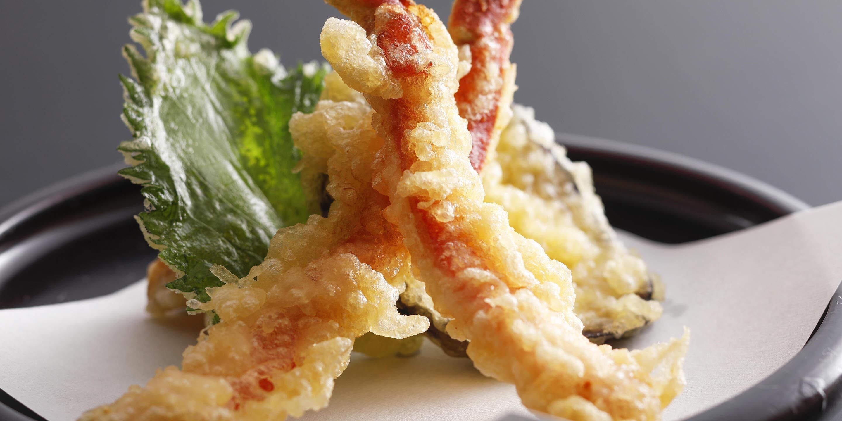 A plate with tempura shrimp and a green leaf garnish.