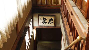 Una escalera de madera tradicional con suelo de esteras de tatami y una obra de caligrafía enmarcada en la pared.