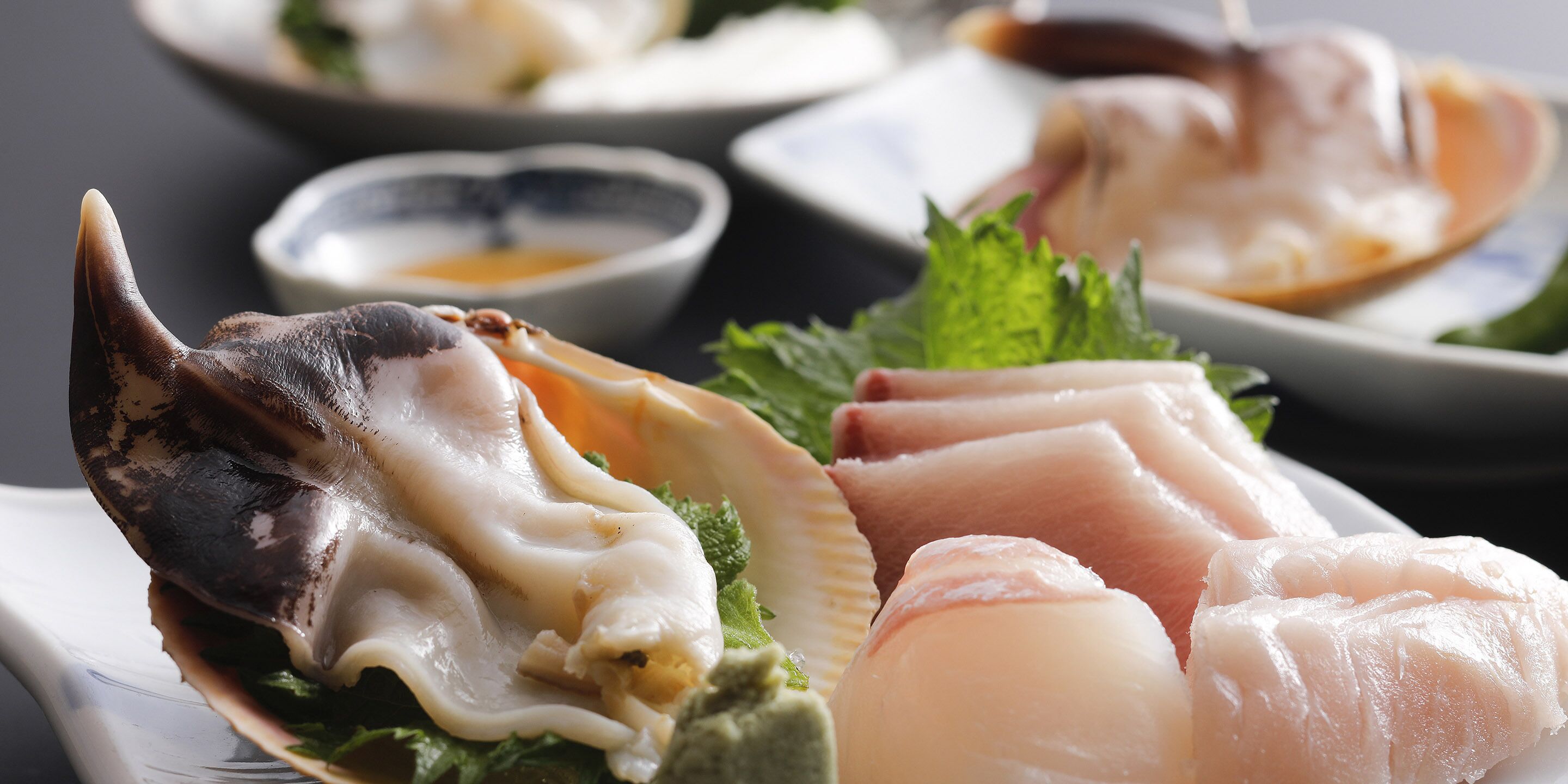 Een close-up van diverse zeevruchten, waaronder oesters en vis, op een bord met een klein schaaltje saus.