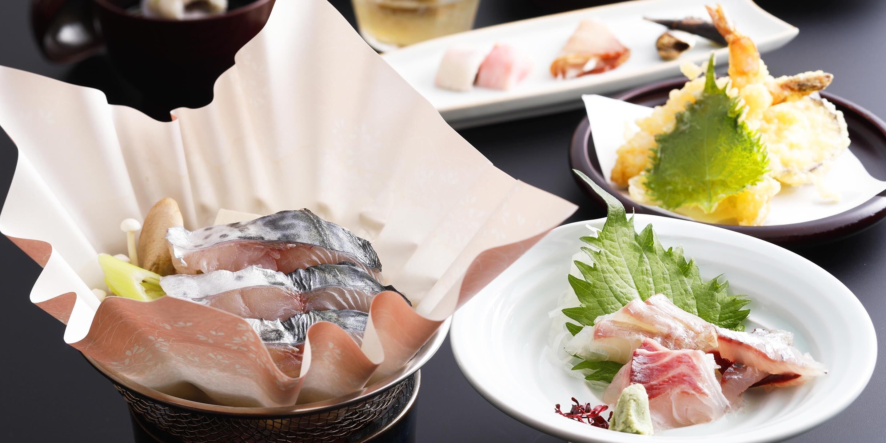 Variedad de platos que incluyen sashimi, tempura y un tazón de pescado.