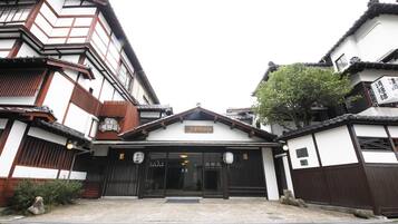 A traditional Japanese building with a wooden facade, a tiled roof, and a sign indicating a restaurant.