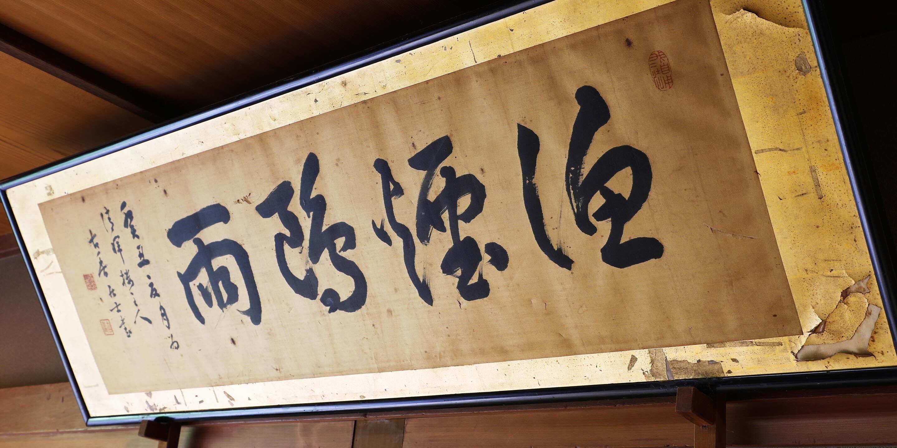 A wooden sign with black calligraphy.