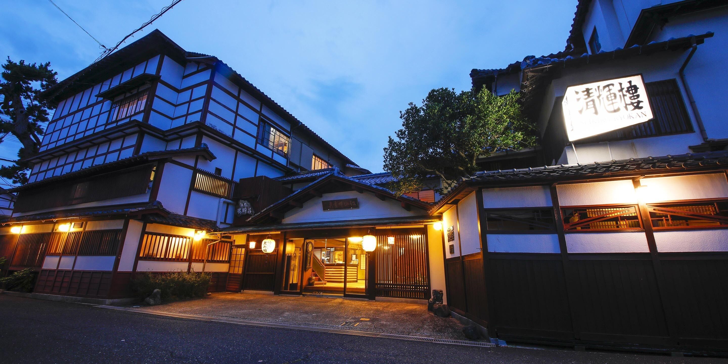 Un bâtiment traditionnel japonais, doté d’une enseigne, de portails en bois et d’une entrée bien éclairée.
