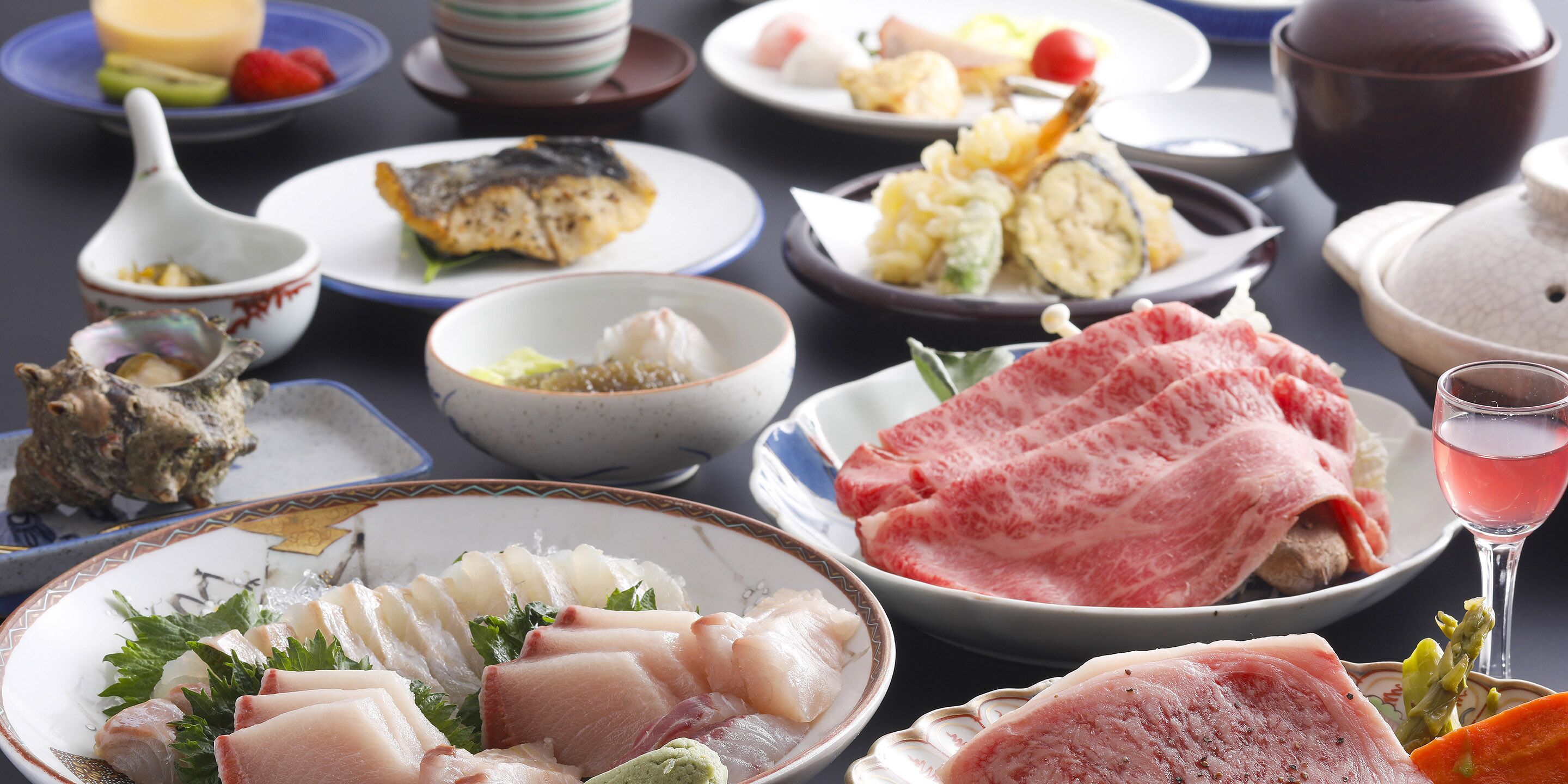 Una variedad de platos, incluyendo sashimi, sushi y otras especialidades de la cocina japonesa, dispuestos sobre una mesa.