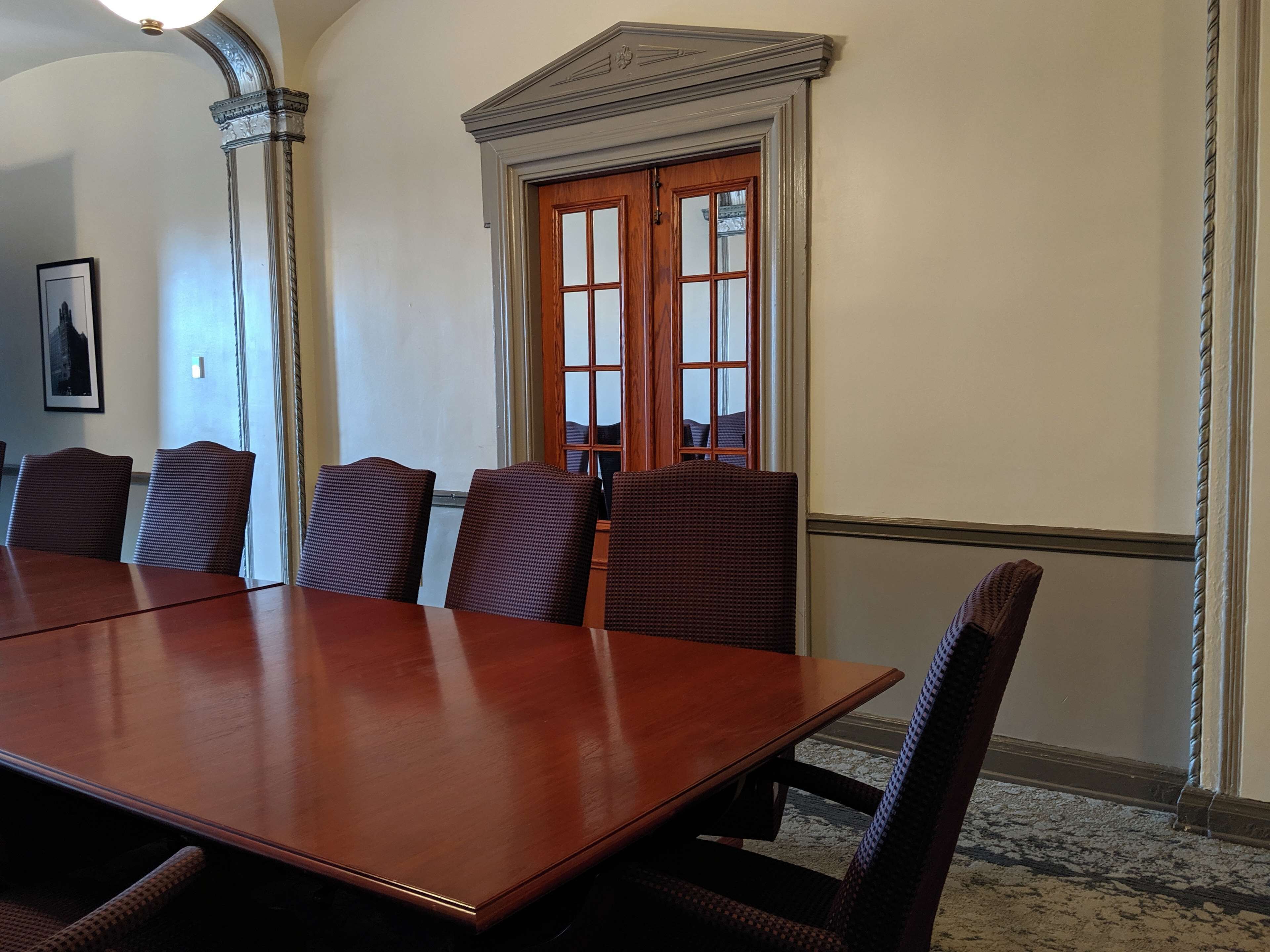 A conference room with a large wooden table and six wicker chairs.