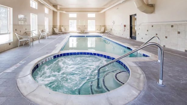 A large indoor swimming pool with a hot tub, surrounded by lounge chairs and a tiled floor. - Grand Vista Hotel Parachute (Parachute)
