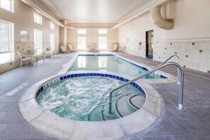 A large indoor swimming pool with a hot tub, surrounded by lounge chairs and a tiled floor. - Grand Vista Hotel Parachute (Parachute)