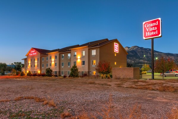 A Grand Vista Hotel with a modern design, multiple floors, and a parking lot in front.