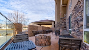 An outdoor patio with stone walls, wooden benches, and a fire pit. - Grand Vista Hotel Parachute (Parachute)