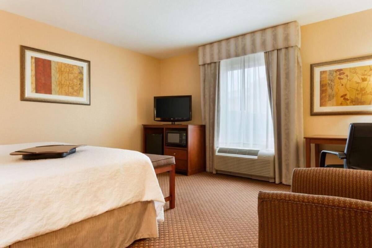 Ett hotellrum med en säng, en tv, ett skrivbord och en stol.