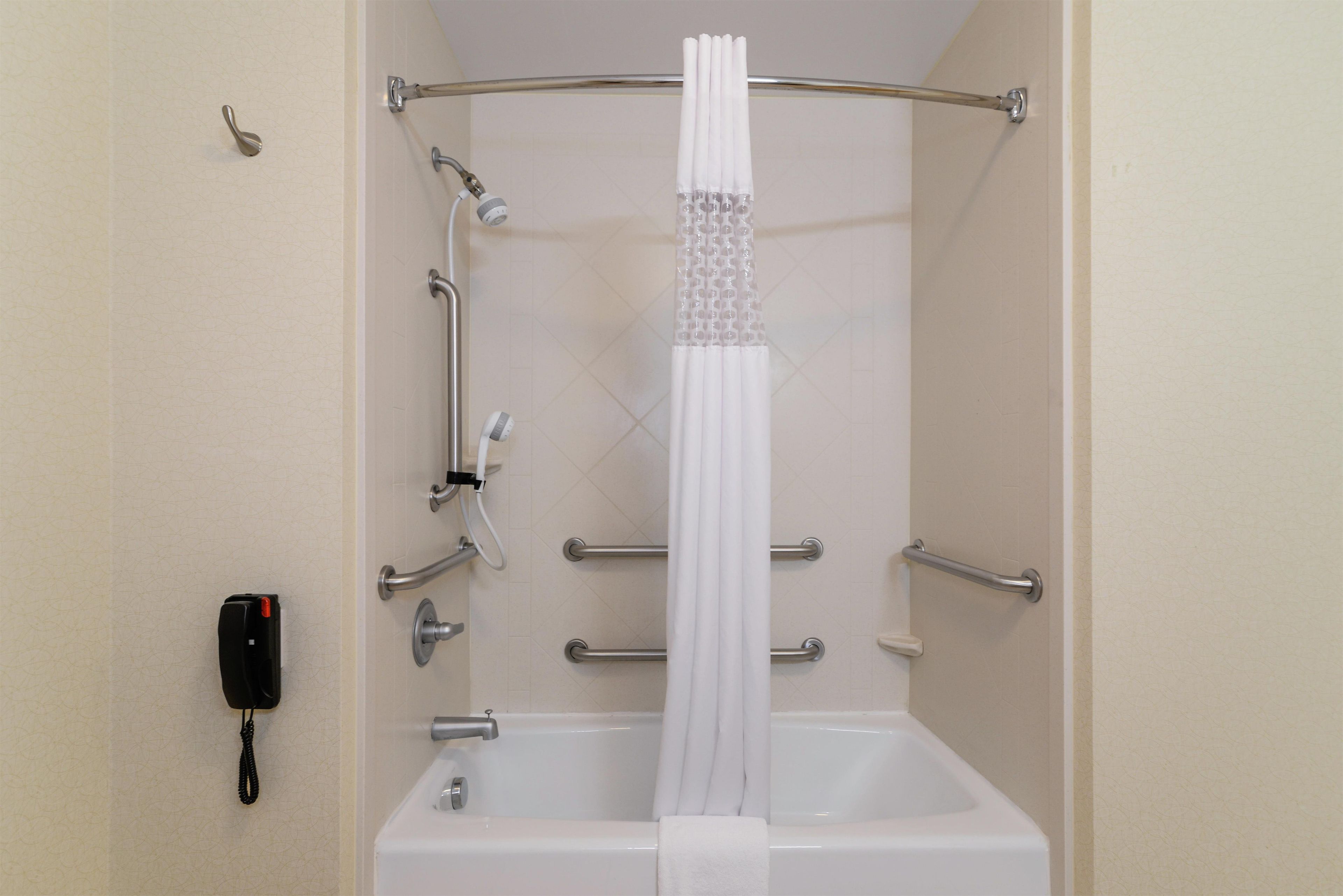 Une salle de bain avec une baignoire, un rideau de douche et un sèche-mains.