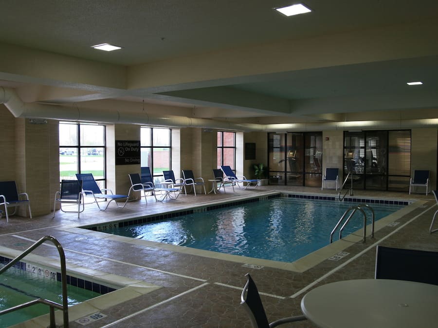 Piscina interior con marcas de carriles bien definidas, sillones de descanso y una mesa junto a la piscina.