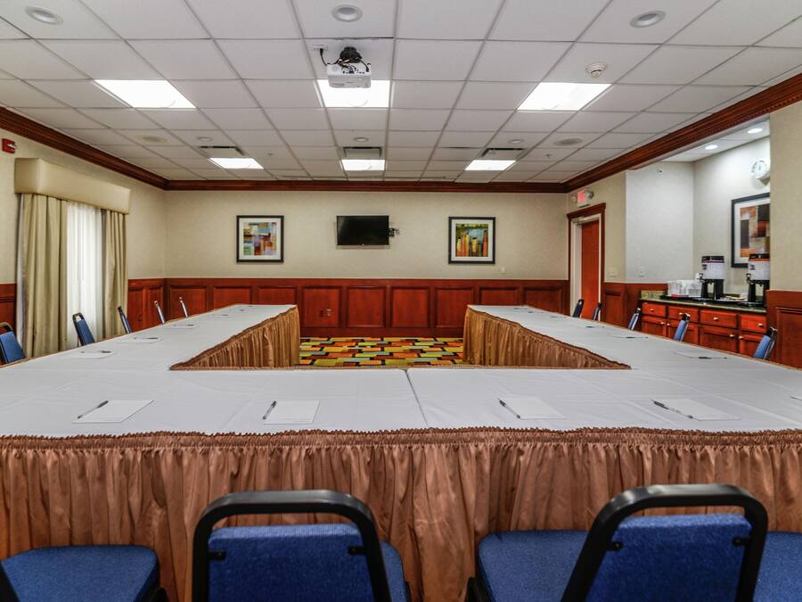 Ett konferensrum med ett långt bord, stolar, en projektor och konstverk på väggarna.