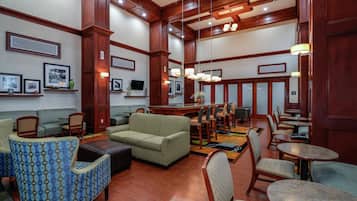 A hotel lobby with a seating area, a television, and a bar.