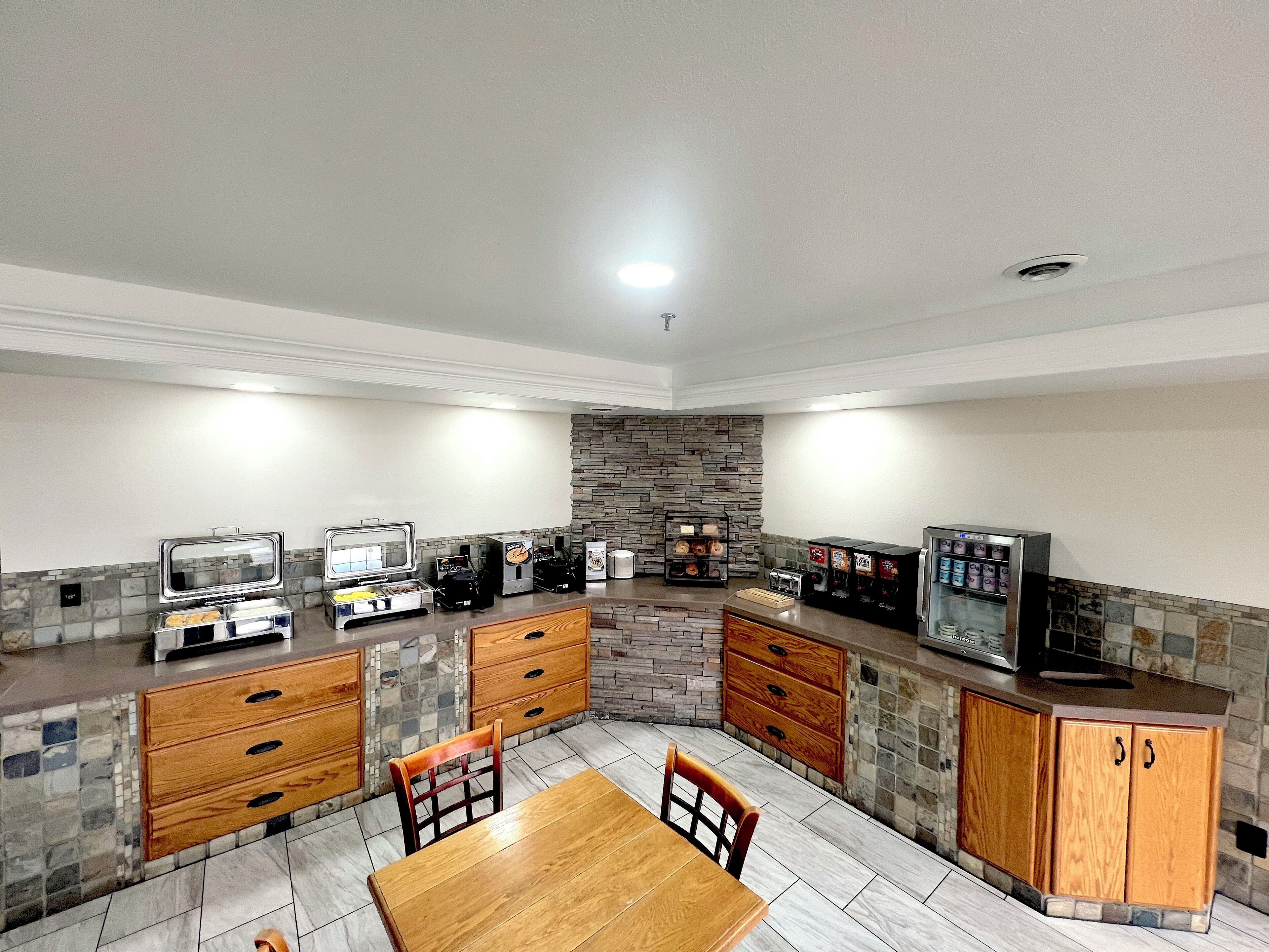 A compact kitchen with a dining area, equipped with a buffet, a coffee machine, and a microwave.