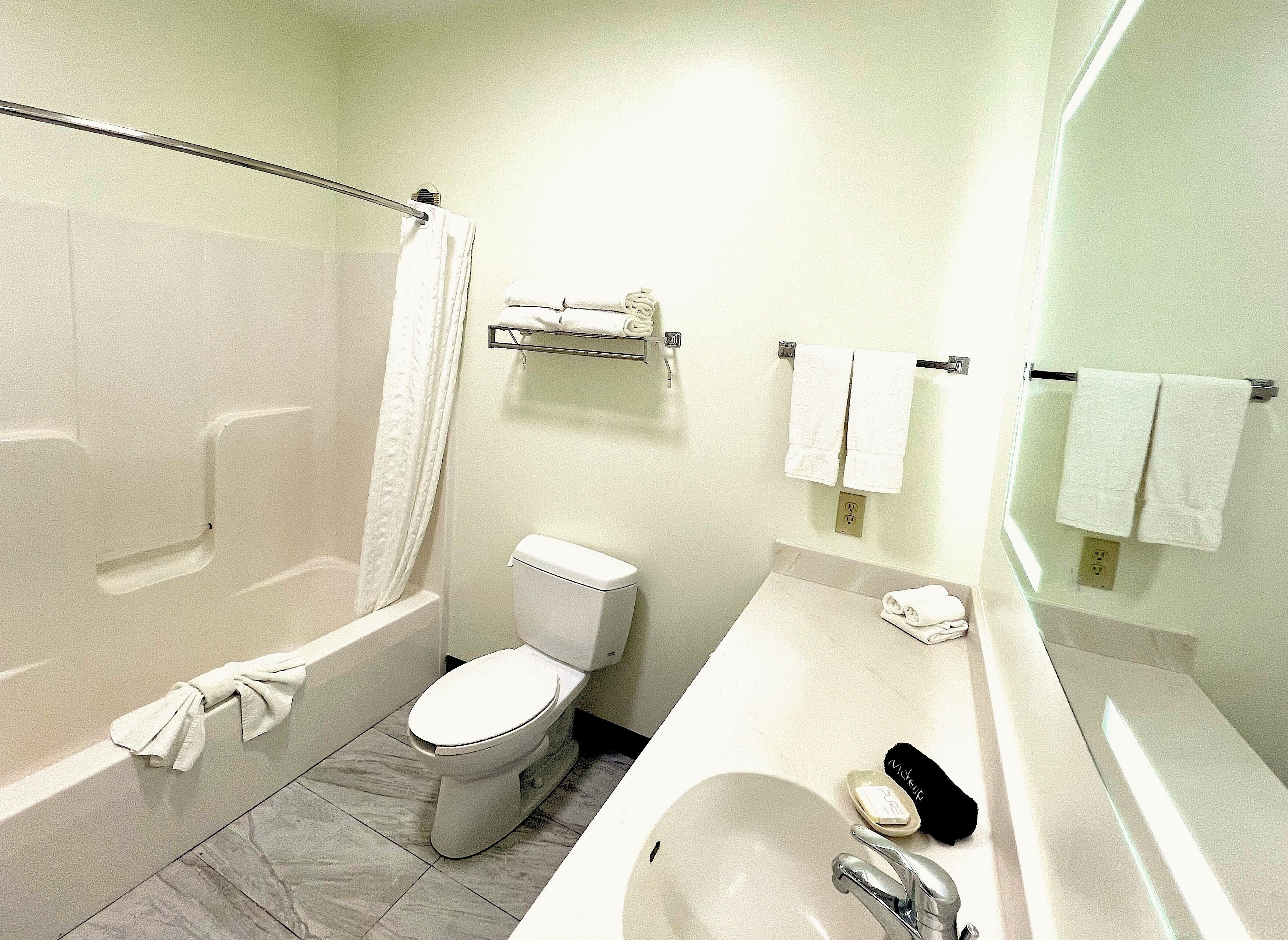 A bathroom with a bathtub, toilet, sink, and a mirror.