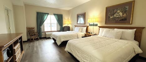 Habitación de hotel con dos camas, un escritorio, una silla, una lámpara y un cuadro en la pared.