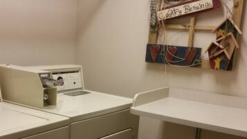 A laundry room with a washing machine, dryer, and a wall-mounted wooden sign that reads "Country Blessings."