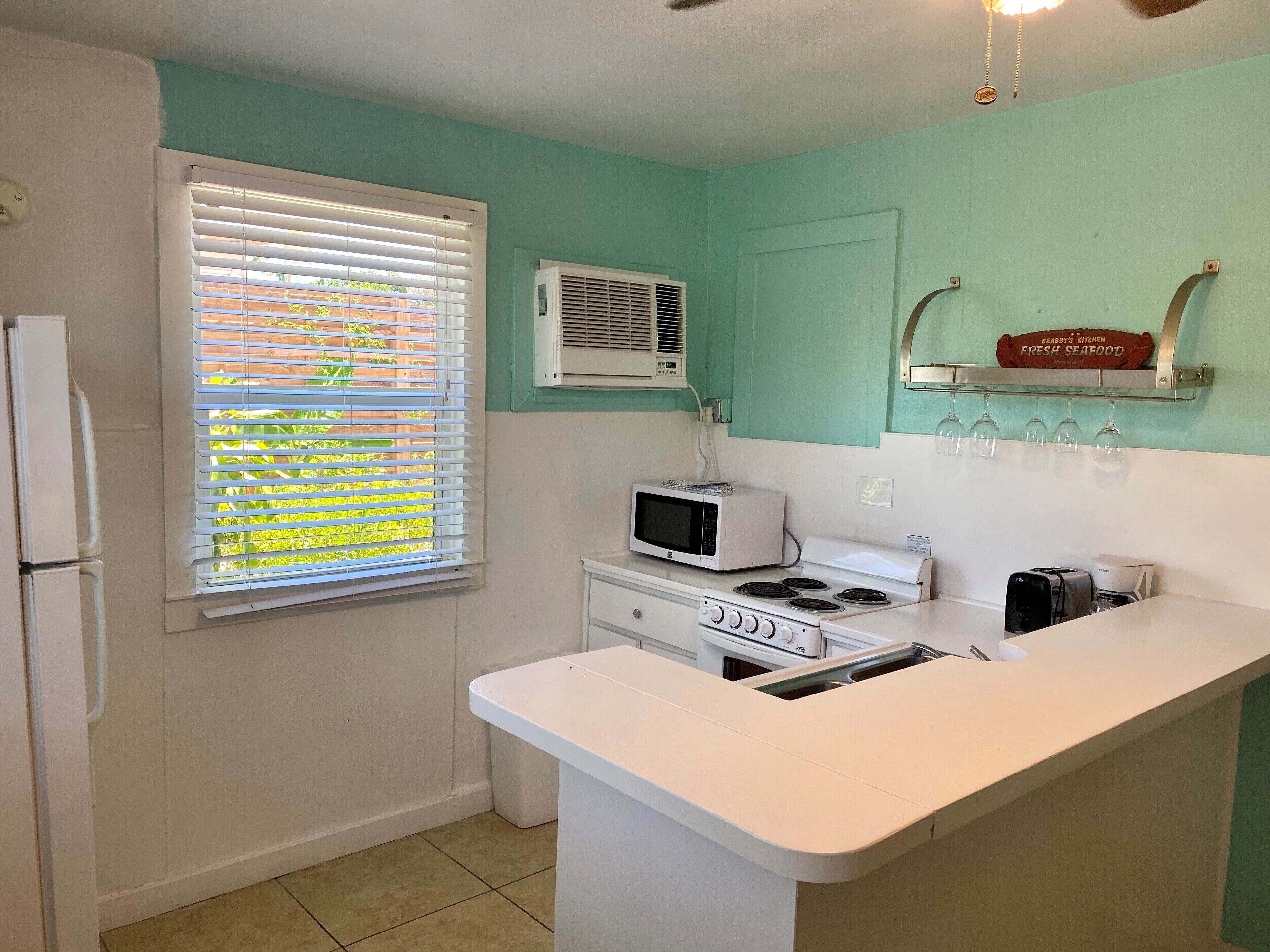 A compact kitchen with a refrigerator, microwave, stove, and a small countertop.