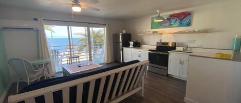 A compact kitchen with a dining area, a ceiling fan, and a view of the ocean.