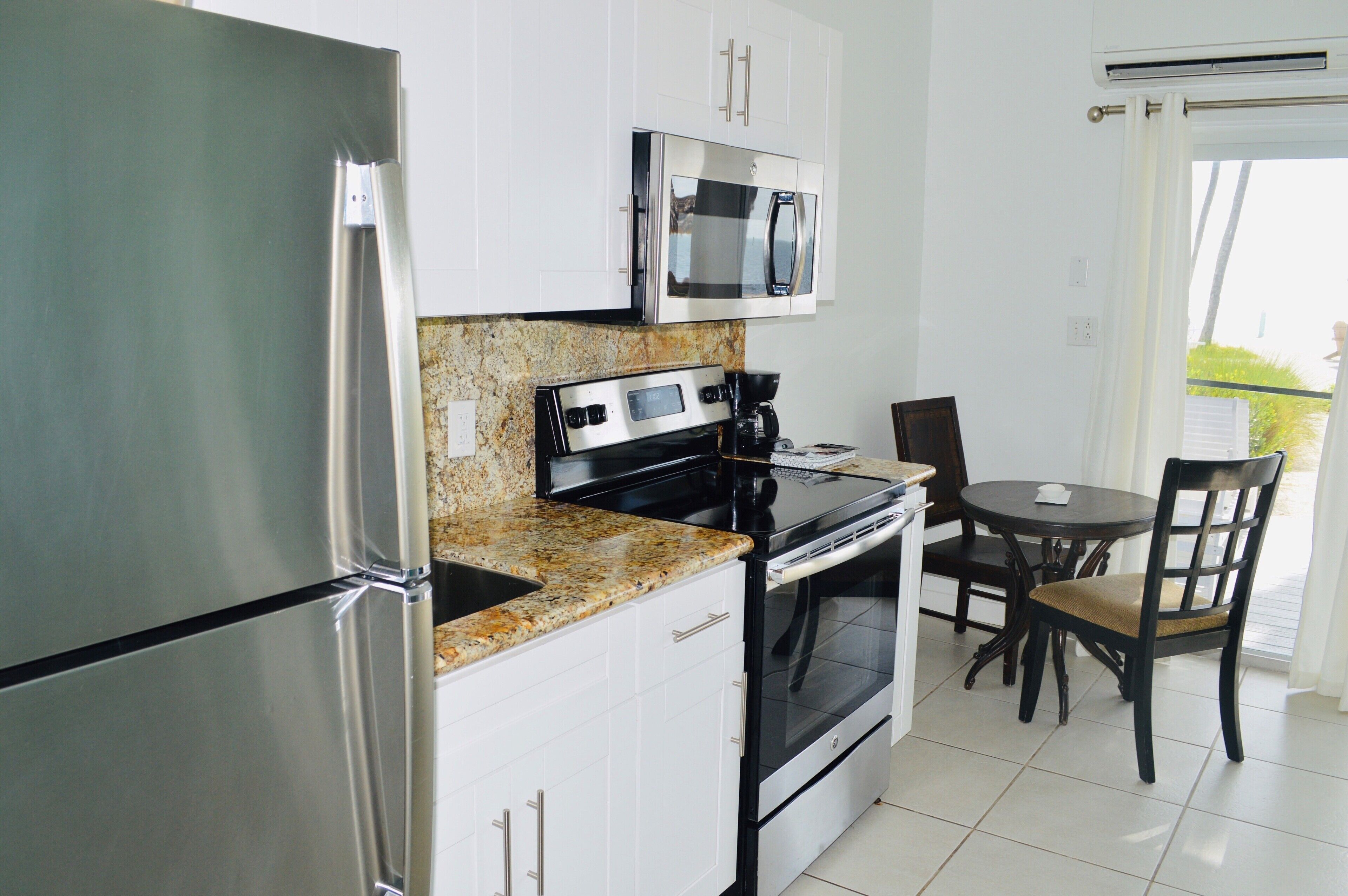 A modern kitchen with stainless steel appliances, granite countertops, and a dining area with a table and chairs.