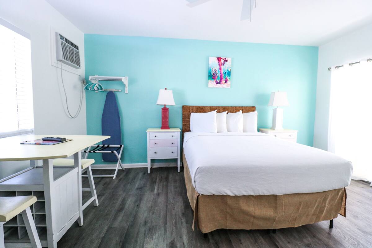 A bedroom with a bed, bedside tables, a desk, and a chair.