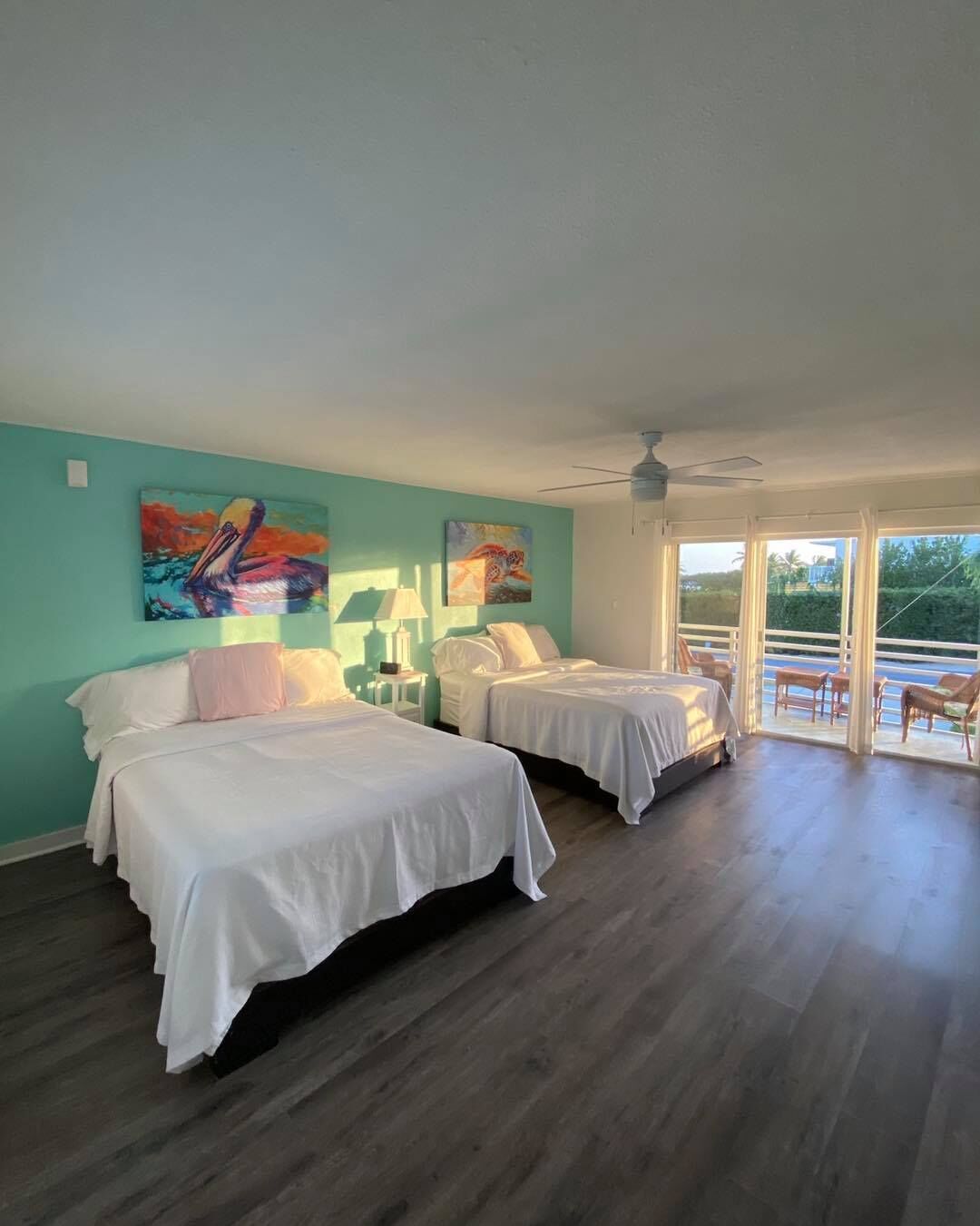 Quarto com duas camas, ventilador de teto e obras de arte nas paredes.