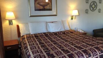Une chambre d’hôtel avec un grand lit, deux lampes de chevet, un tableau encadré au mur et un téléphone sur la table de chevet.