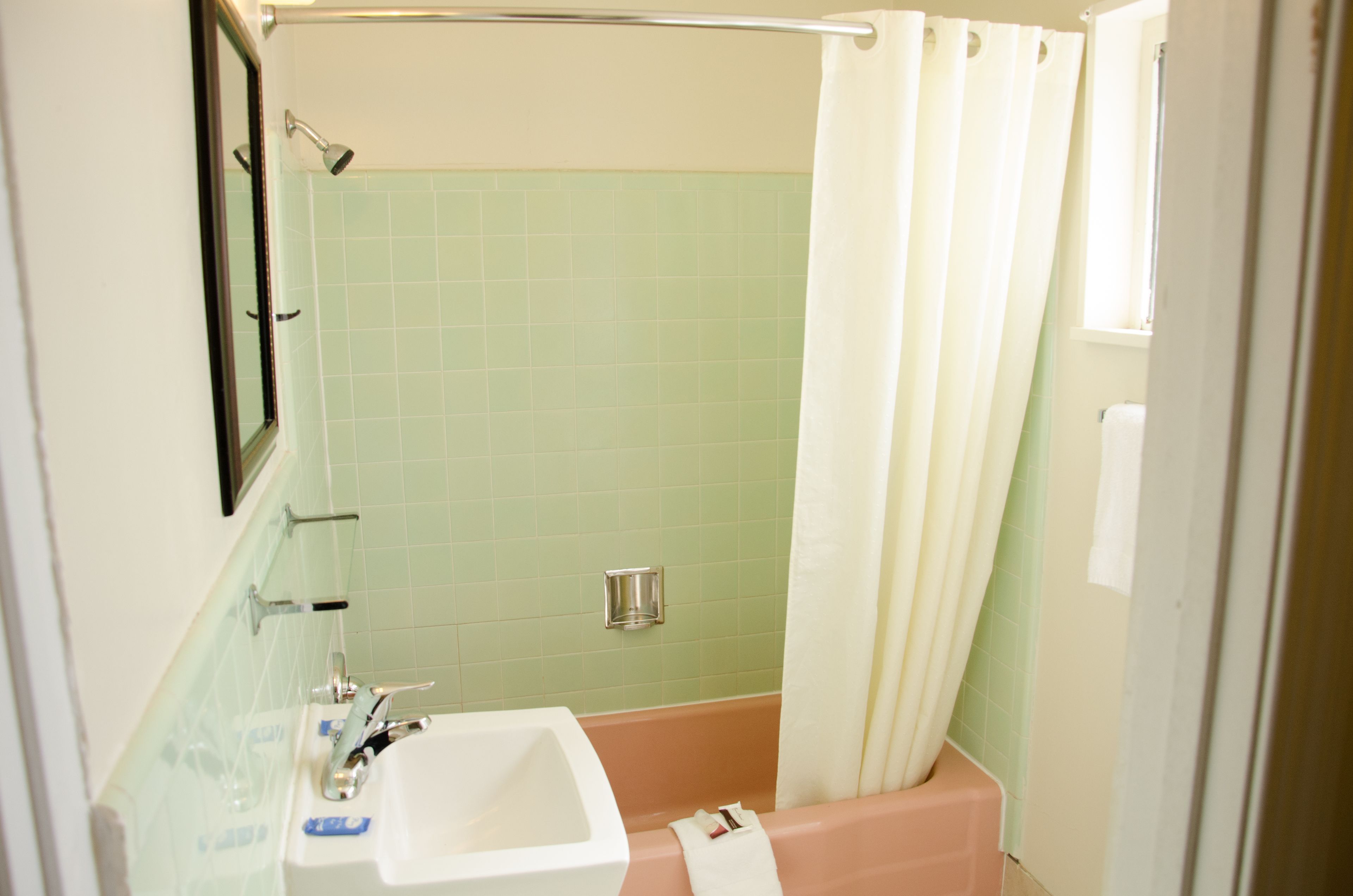 A bathroom with a sink, mirror, and shower area.