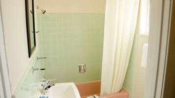 A bathroom with a sink, mirror, and shower area.