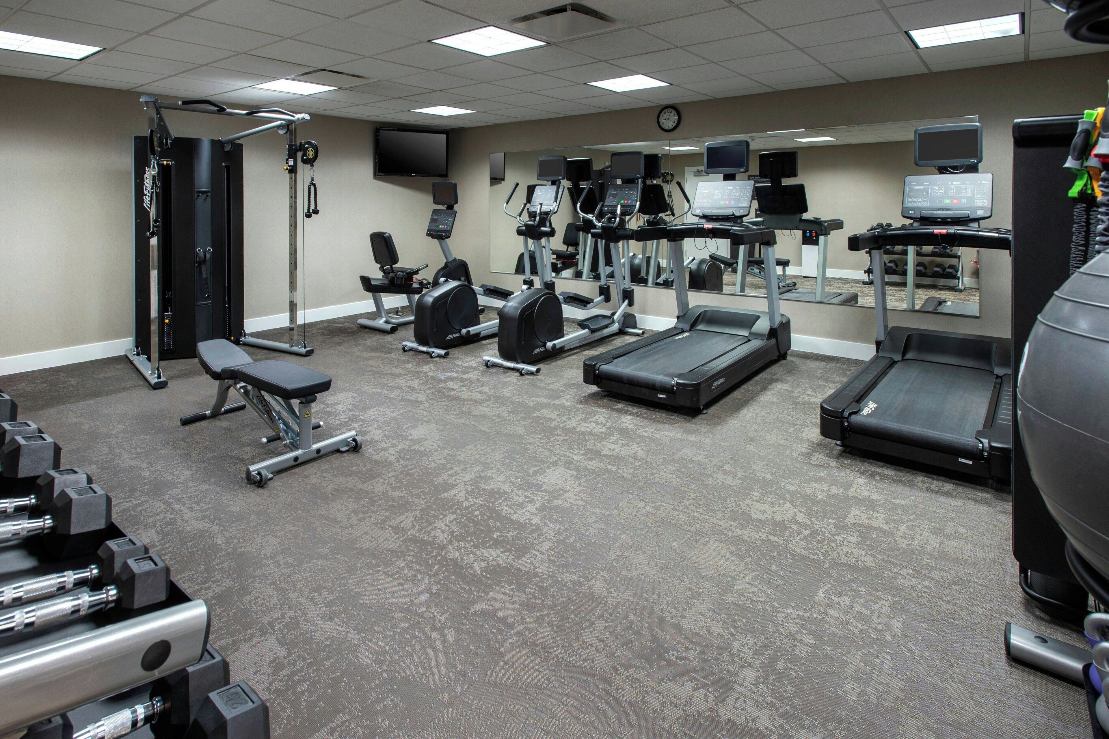 A gym with various exercise equipment including treadmills, weight machines, and free weights.