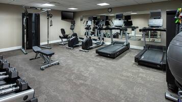 A gym with various exercise equipment including treadmills, weight machines, and free weights.